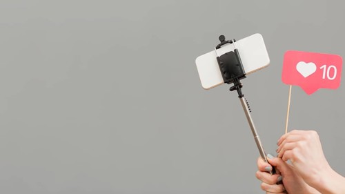 Close up blogger holding selfie stick with mobile phone