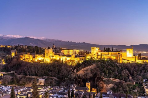 View from the Mirador de San Nicolas of Alhambra and the snow-capped mountains of the Sierra Nevada at dusk