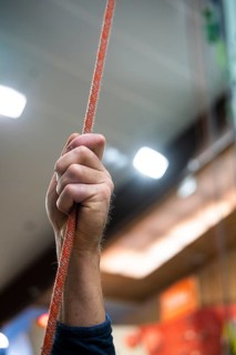 A person holding a rope for belaying in a climbing gym