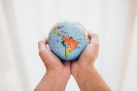 Person s hand holding small globe