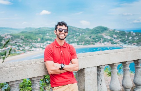 Portrait of smiling tourist in a viewpoint of a bay. Handsome tourist man looking at the bay of San Juan del Sur