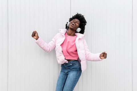 Portrait young woman with headphones jumping