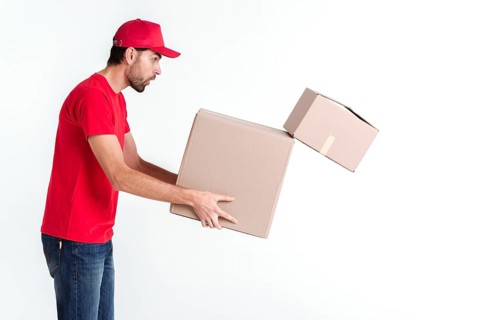 Side view delivery boy holding parcel post boxes drops one