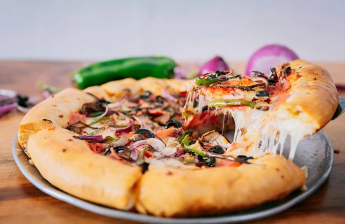 Close up of spatula taking a slice of supreme pizza with vegetables. Spatula taking a slice of supreme pizza with spatula