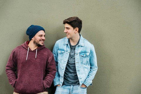 Young friends standing near grey wall
