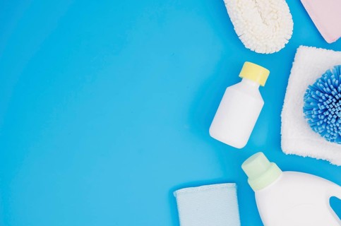 Different type sponges with detergent bottles blue backdrop