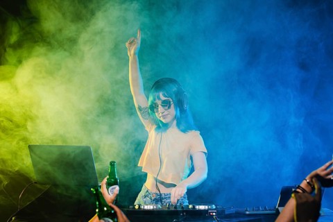Entertaining female dj with hand raised