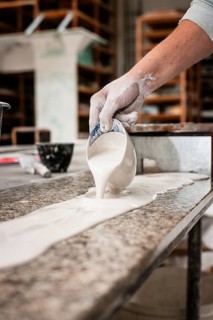 A plasterer pours plaster onto a workbench
