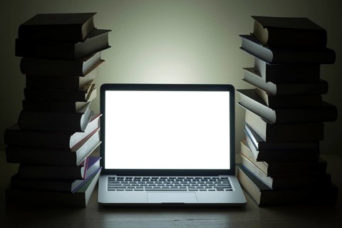 Laptop dark stacked books