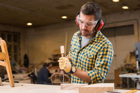 Close up carpenter hitting hammer chisel wooden block workshop