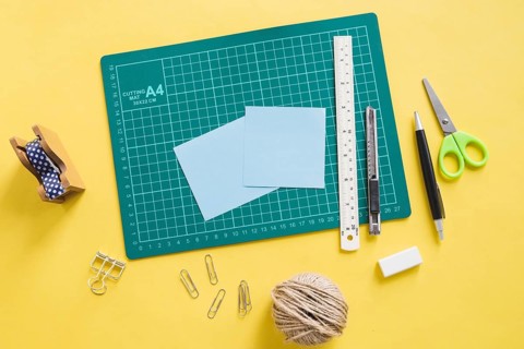 Elevated view green cutting mat stationeries yellow background