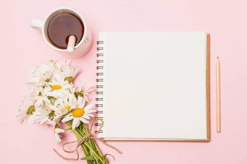 Notebook near flowers cup drink
