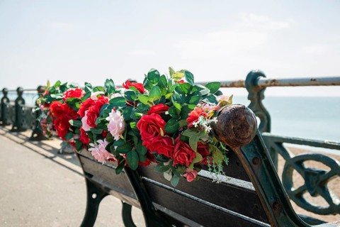 A bench with plastic flowers on the promenade in Brighton