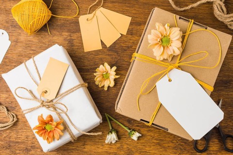 Wrapped gift tied with tag string beautiful flower wooden surface