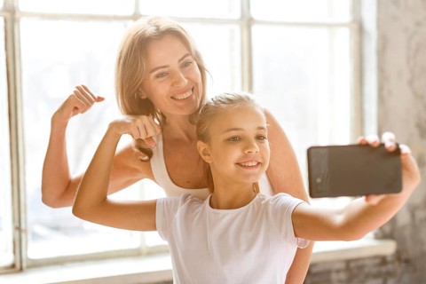 Mother daughter taking selfie flexing arm muscles