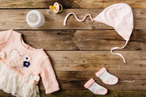 Pink baby s dress with headwear pair socks milk bottle pacifier wooden table