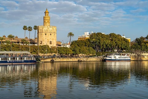 On the banks of the Guadalquivir river with the historic Torre del Oro tower in Seville
