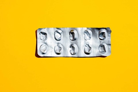 Empty tablet blister pack against yellow background