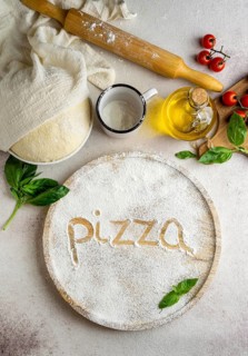 Top view pizza dough with tomatoes word written flour