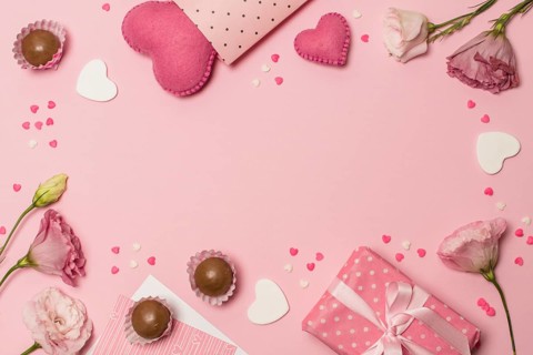 Flowers near hearts present box chocolate candies