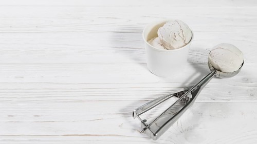 Scoop with ice cream ball near cup