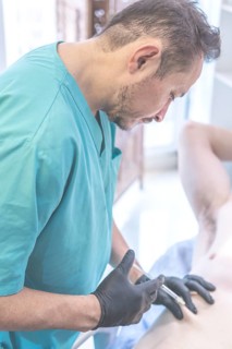Latin doctor injecting anesthesia to patient on operating table