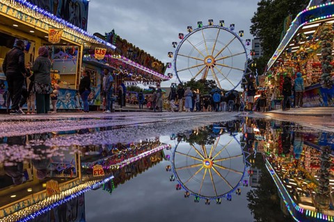 The colourful lights of the Mainfest are reflected in a puddle. The Mainfest on the Mainkai