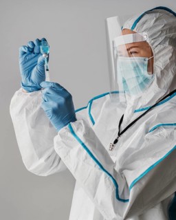 Doctor holding vaccine bottle while wearing protective equipment