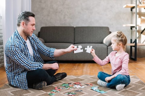 Father daughter hand holding jigsaw puzzle piece