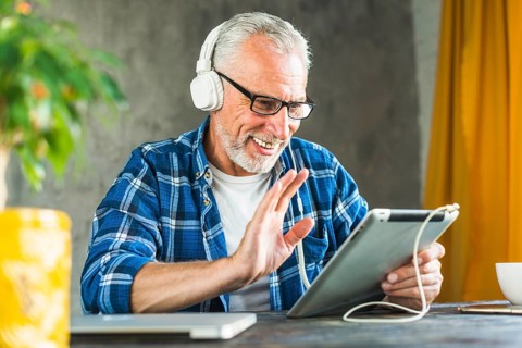 Smiling senior man saying hello digital tablet