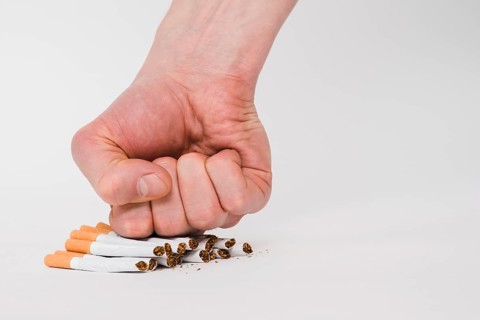 Person fist crushing cigarettes isolated white background