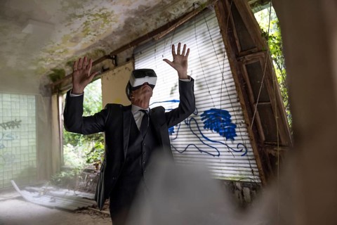 Man dressed in suit wearing VR glasses in a dilapidated office building