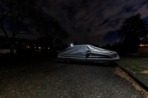 Covered car parked on the street under a lamppost at night