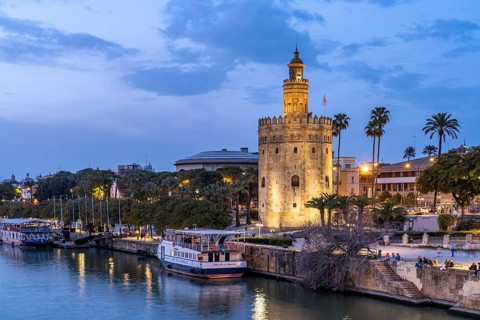On the banks of the Guadalquivir River with the historic Torre del Oro tower at dusk