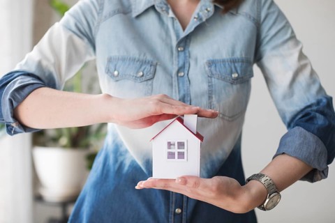 Midsection woman protecting house model office