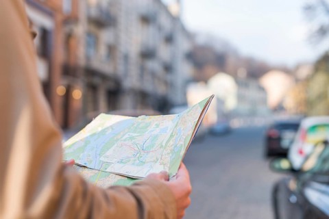 Close up male traveler holding map hand standing city street