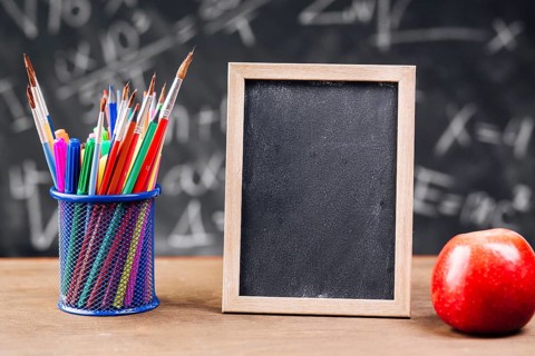 Pen stand blank chalkboard with apple placed desk
