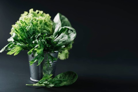 Organic leafy vegetables bucket black background