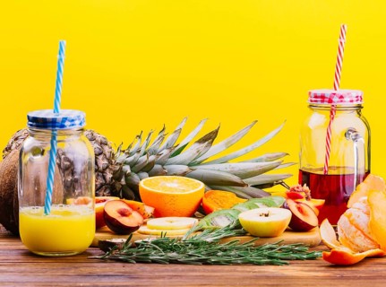 Fruits rosemary juice mason jar chopping board against yellow backdrop