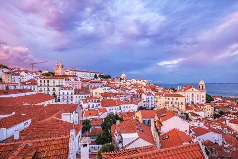 View of Lisbon famous view from Miradouro de Santa Luzia tourist viewpoint over Alfama old city district on sunset with dramatic overcast sky. Lisbon