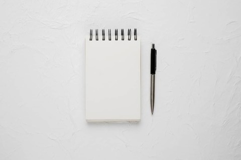 High angle view white blank spiral notepad with ballpoint pen