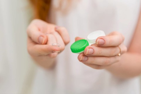 Woman hand holding contact lens it s container