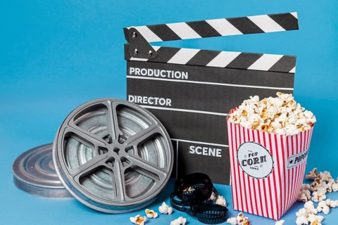 Film reels film strips clapperboard with popcorn box blue background