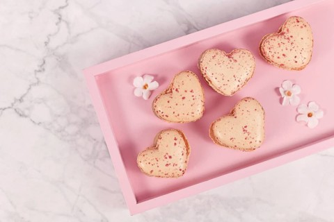 Sweet heart shaped French macaron sweets on pink tablet