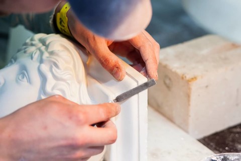 A plasterer restores a stucco figure