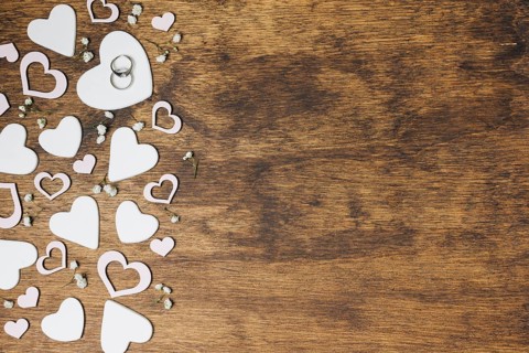 Overhead view silver wedding rings heart shape wooden backdrop