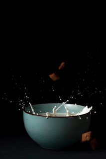 Cereals falling on a bowl with splashing milk