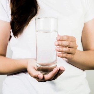 Crop female hands holding glass water
