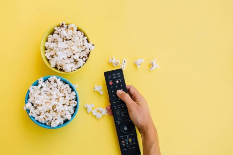 Crop hand remote control near popcorn