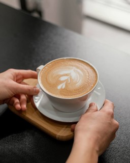 Female barista placing decorated cup coffee counter